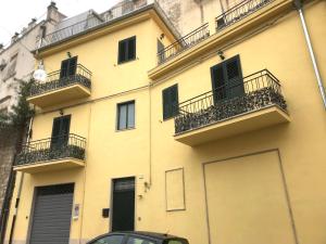 a yellow building with balconies and a car parked in front at Casa Alva in Ragusa