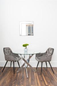 a glass table and two chairs in a room at Howburn Residence Serviced Apartments - 1,2& 3 Bedroom Apartments in Aberdeen