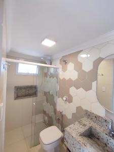uma casa de banho com um WC, um lavatório e um espelho. em Ybira Loft em Araxá