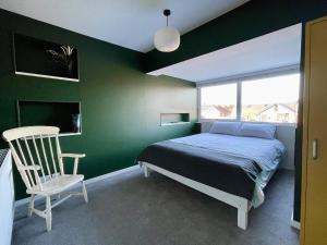 a bedroom with green walls and a bed and a chair at Island House in Colchester