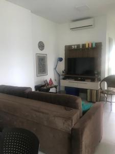 sala de estar con sofá y TV de pantalla plana en Apartamento encantador, 100 m do mar, en Porto Belo