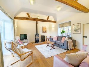 a living room with a couch and chairs and a tv at Holme Street House and Dove Cote Lodge in Pulborough