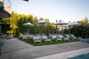 a group of lounge chairs and umbrellas on a lawn at Garden City Resort in Kalamata
