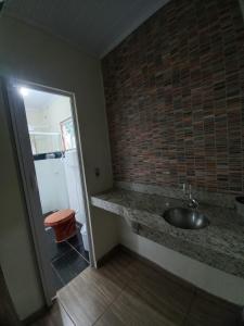 a bathroom with a sink and a brick wall at Chalés Ocaso in Sao Jorge
