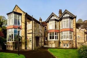 a large brick house with windows and a yard at Sir William Hotel in Grindleford Bridge