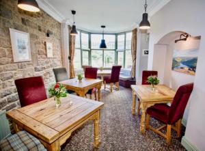 Sir William Hotel في Grindleford Bridge: غرفة طعام مع طاولات خشبية وكراسي حمراء