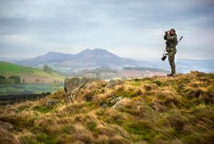 un hombre parado en la cima de una colina en Red Lion, Coorie Inn, en Earlston