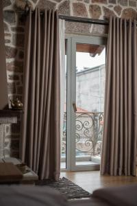 una ventana abierta con cortinas en una habitación en George Boutique Hotel, en Voskopojë