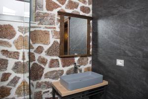baño con lavabo azul y pared de piedra en George Boutique Hotel, en Voskopojë