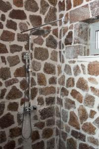 y baño con ducha y pared de piedra. en George Boutique Hotel, en Voskopojë