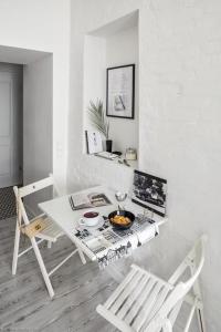a white dining room with a table and chairs at Bunga Apartament in Warsaw