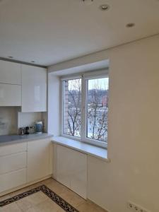 uma cozinha com armários brancos e uma janela em River view appartment in Kaunas em Kaunas