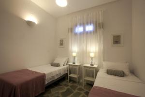 a bedroom with two beds and a window and two lamps at Kallisti Daphne · Gorgeous Villa - an oasis for 8 people in Naousa