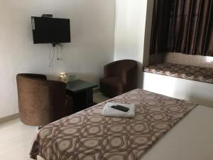 a room with a bed and a chair and a television at Roop Shree Hotel in Chittaurgarh