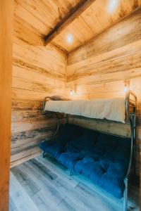 a bed in a wooden room with a wooden ceiling at RUKAKUTRAL refugio de bosque in Pucón