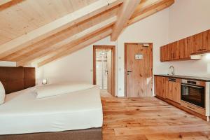 a bedroom with a white bed and wooden floors at Landhotel Berger in Ainring