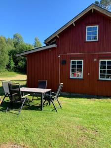 a picnic table and chairs in front of a red barn at Rabben in Årjäng