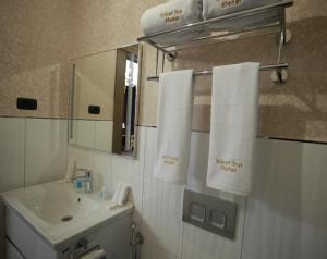 een badkamer met een wastafel, een spiegel en handdoeken bij West inn Hotel & Restaurant in Baku