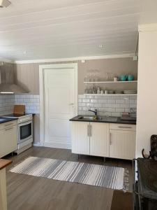 una cucina con armadietti bianchi e una porta bianca di Rabben a Årjäng