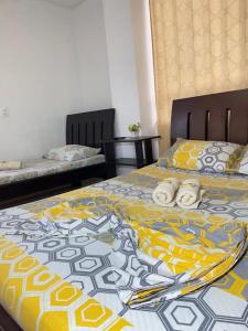 1 dormitorio con 2 camas con manta amarilla y azul en Hospedaje Balcones de la Colina, en Floridablanca