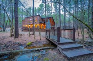une cabane en rondins dans les bois avec un pont et une maison dans l'établissement Fireside Creek Luxury Cabin, à Stephens Gap