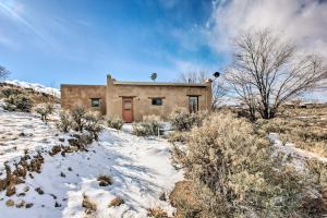 una casa en una colina cubierta de nieve con un edificio en Casita Vacation Rental Near Taos with Patio! en El Prado