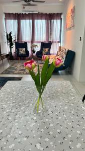 eine Vase mit Blumen auf einem Tisch im Wohnzimmer in der Unterkunft D Naurah Meritus Guesthouse in Perai