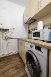 eine Küche mit einer Waschmaschine und einer Mikrowelle in der Unterkunft Luxury Radox Apartment Park 1 BZ in Buzău