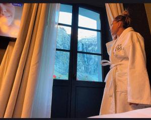 uma mulher de robe a olhar pela janela em Hôtel du cirque et de la cascade em Gavarnie