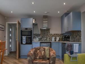 a kitchen with blue cabinets and a chair in a room at The Boat House At Tides Reach in West Mersea