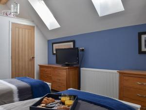 a bedroom with blue walls and a tv and a tray of food at The Boat House At Tides Reach in West Mersea