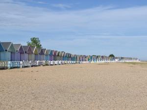 a row of colorful beach huts on a beach at The Boat House At Tides Reach in West Mersea