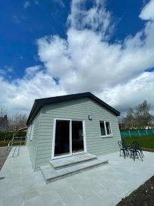 a small green building with a patio at Pine Lodge in Lisnaskea