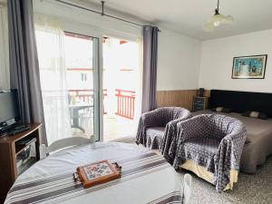 a bedroom with a bed and two chairs and a window at Appartement Cambo-les-Bains, 1 pièce, 2 personnes - FR-1-495-16 in Cambo-les-Bains