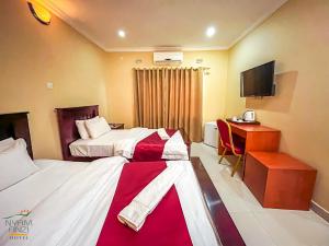 a hotel room with two beds and a desk and a television at Nyamfinzi Hotel in Chipata