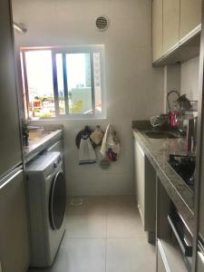 cocina con lavadora y ventana en Apartamento encantador, 100 m do mar, en Porto Belo