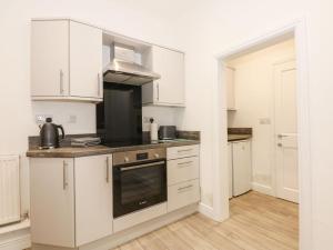 La cuisine est équipée de placards blancs et d'un four avec plaques de cuisson. dans l'établissement Sea Breeze Apartment No 9, à Hunstanton