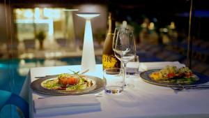 una mesa con dos platos de comida y una botella de vino en Hotel President en Lignano Sabbiadoro