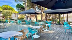una terraza con mesas, sillas y sombrillas en Hotel President en Lignano Sabbiadoro