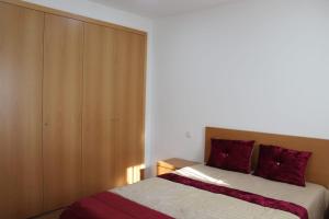 a bedroom with a bed with red pillows and a closet at Casa do Iteiro in Caniçada +26 photos