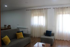 a living room with a couch and two windows at Casa do Iteiro in Caniçada