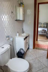 La salle de bains est pourvue de toilettes blanches et d'un lavabo. dans l'établissement Chacara com piscina e lazer em Jaboticatubas MG, à Jaboticatubas