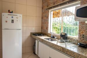 La cuisine est équipée d'un réfrigérateur blanc et d'un évier. dans l'établissement Chacara com piscina e lazer em Jaboticatubas MG, à Jaboticatubas