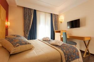 a hotel room with a large bed and a desk at Hotel Luna Riccione e Aqua Spa Only Adults +12 in Riccione