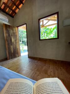 an open book on a bed with a window at Pousada Flor de Laranjeira in Goiás
