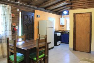 a kitchen with a wooden table and a refrigerator at Peumayen Cabañas in Villa Las Rosas