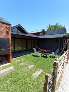 einen Garten mit zwei Stühlen und einer Hängematte vor einem Haus in der Unterkunft Escala Ezeiza Loft con desayuno in Luis Guillón