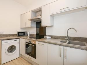 a white kitchen with a sink and a dishwasher at Sea Breeze Apartment No 7 in Hunstanton