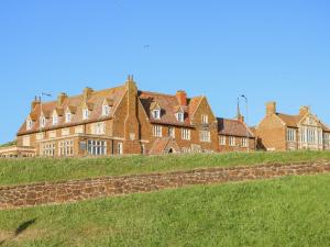 a large brick building on top of a grassy hill at Sea Breeze Apartment No 7 in Hunstanton