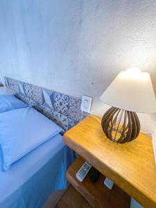 a lamp on a table next to a bed at Pousada Flor de Laranjeira in Goiás
